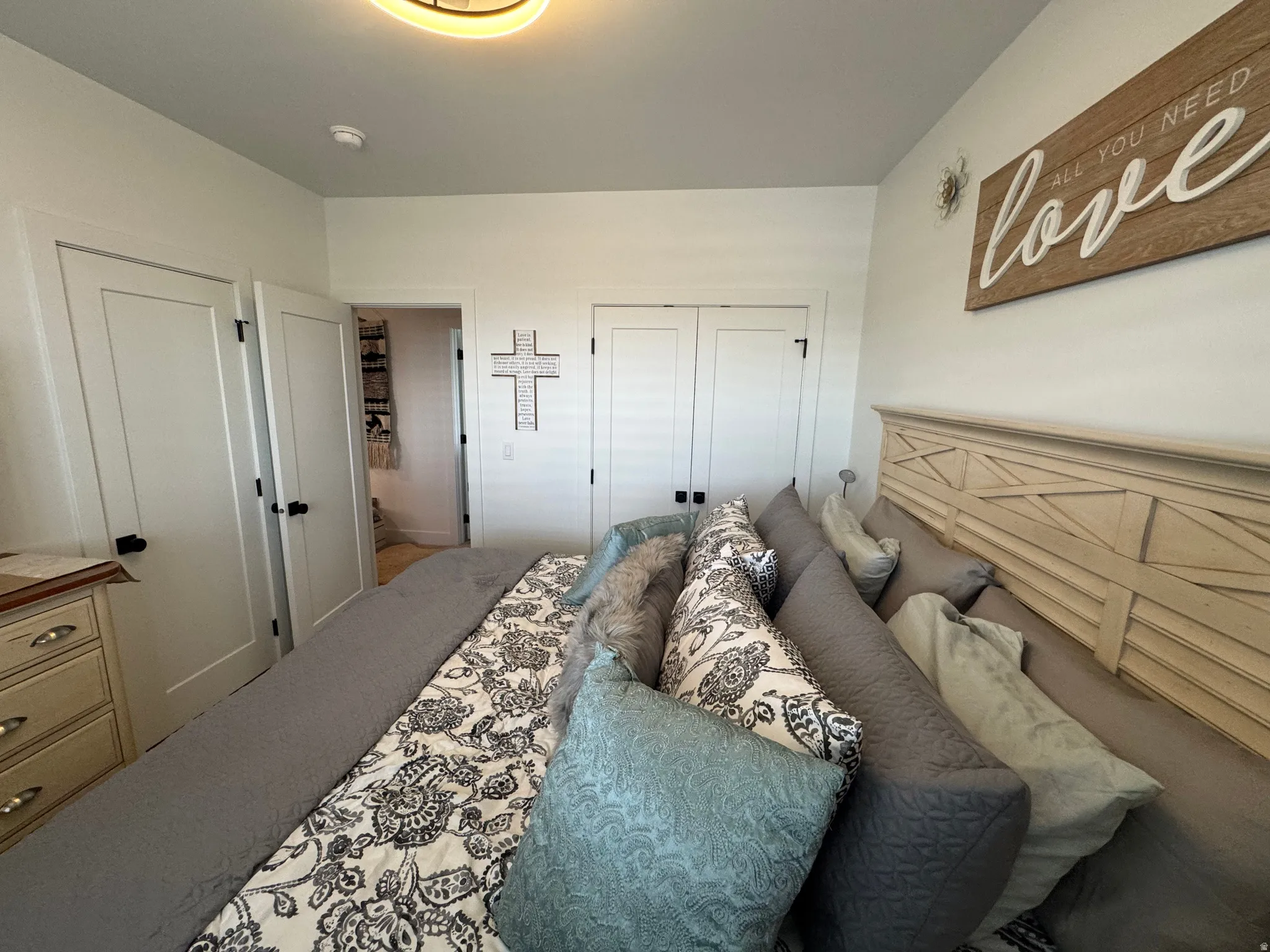 Bright bedroom featuring a decorative light fixture, white walls, and multiple doors with black hardware