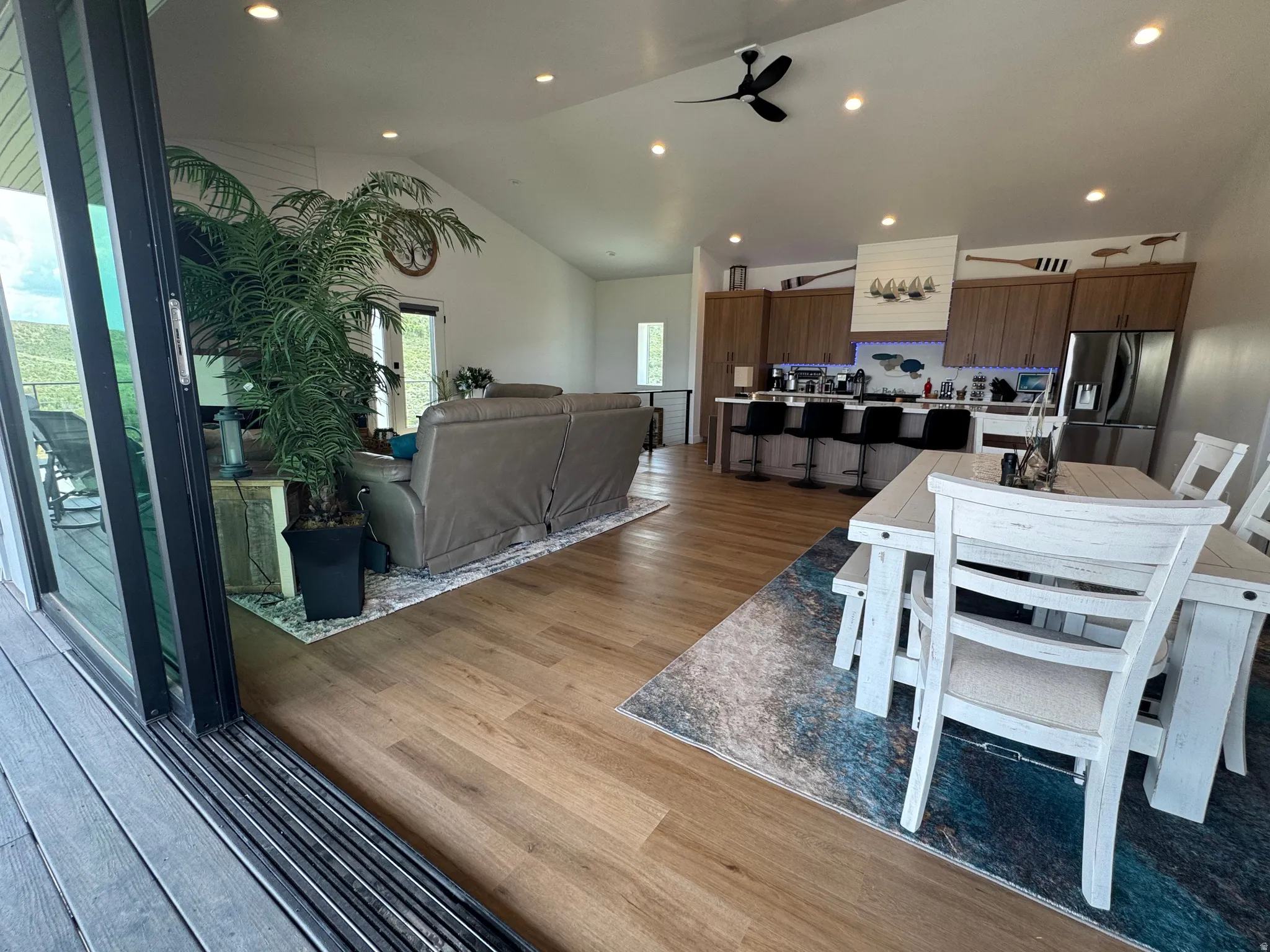 Open-concept living space featuring wood-finish flooring, recessed lighting, and vaulted ceilings