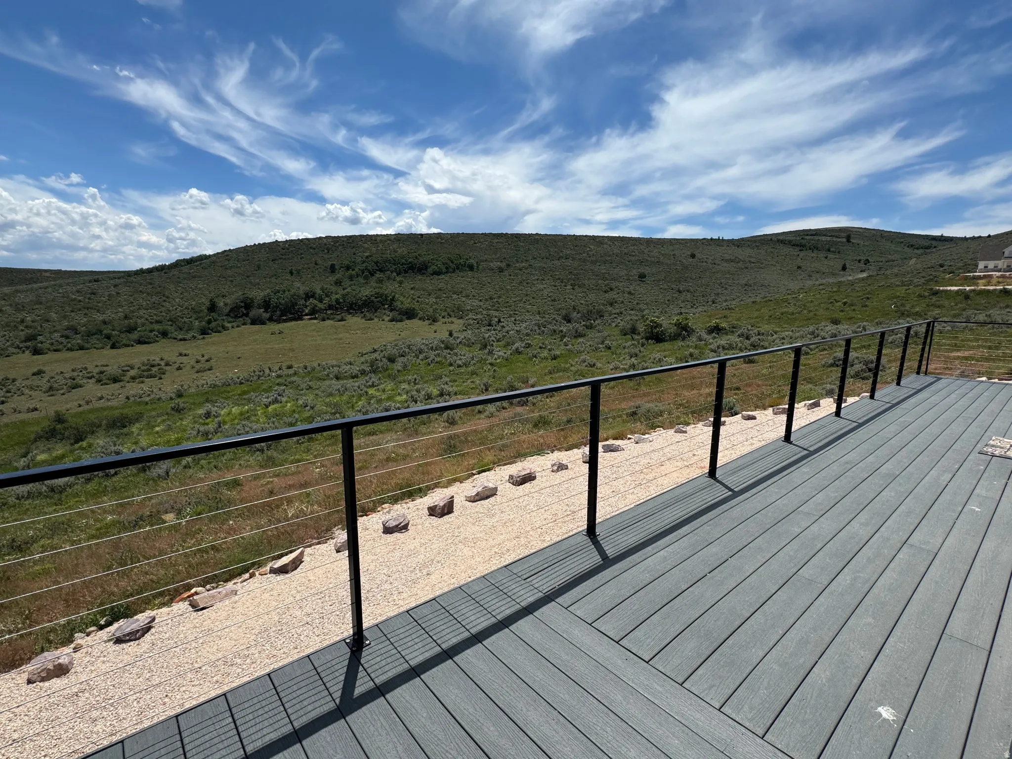 Spacious outdoor deck featuring gray composite decking and contemporary cable railings