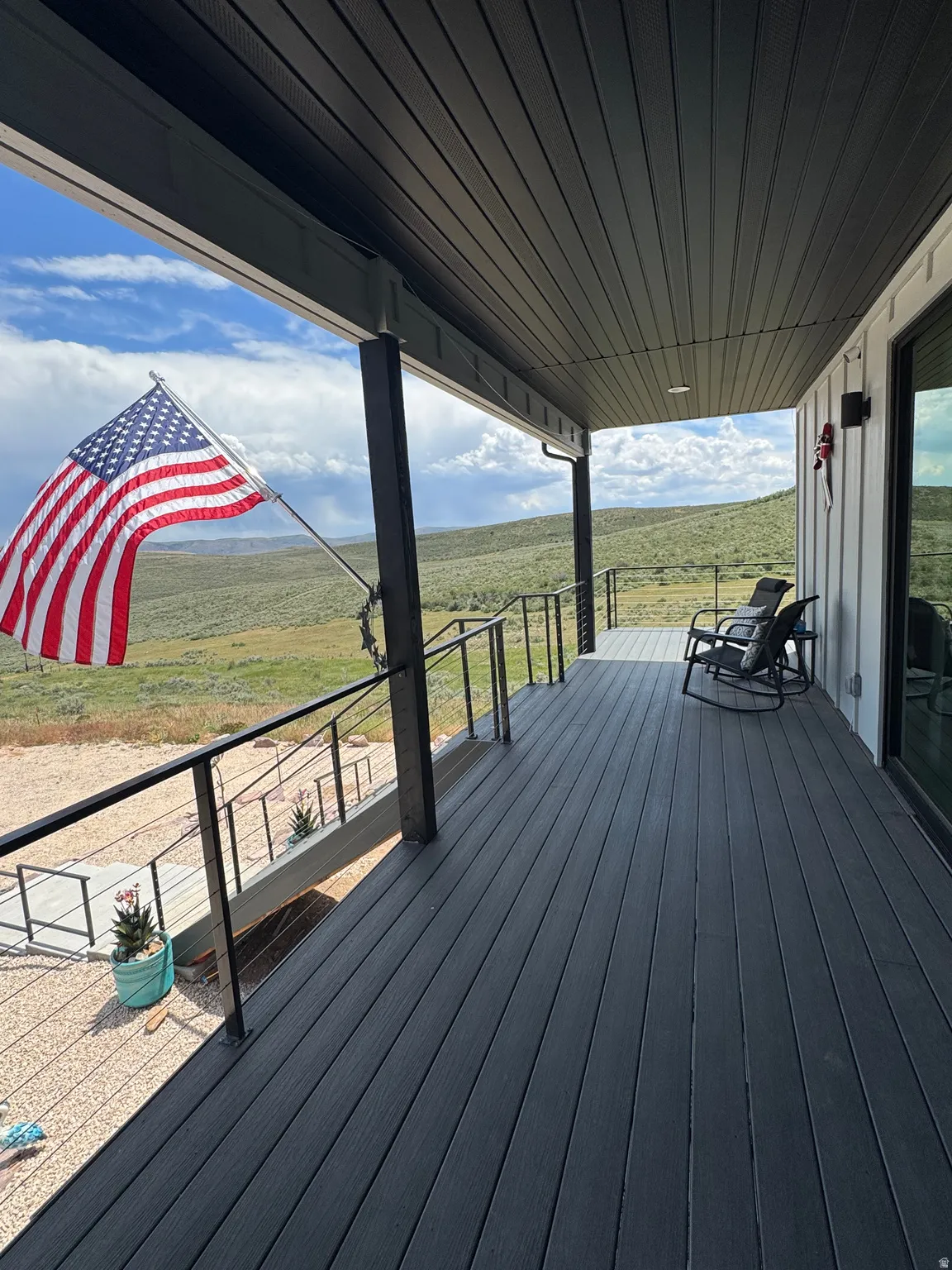 Expansive covered porch featuring dark composite decking and black metal railings