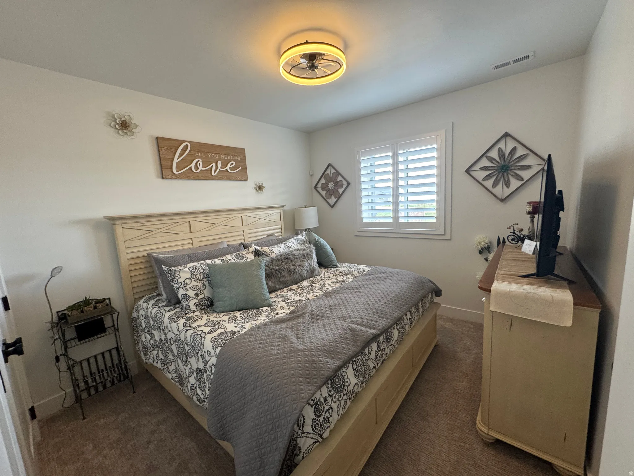 Carpeted interior room featuring a window with plantation shutters, a white ceiling, and a flush-mount light fixture with fan