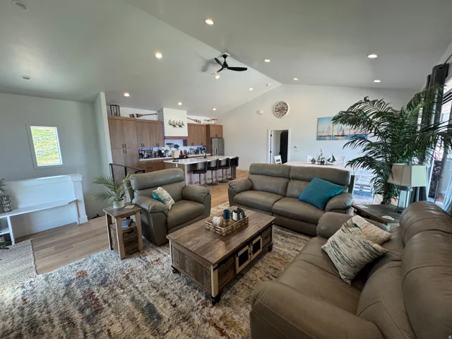 Open-concept living space featuring vaulted ceilings, recessed lighting, wood-finish flooring, and a kitchen island with seating