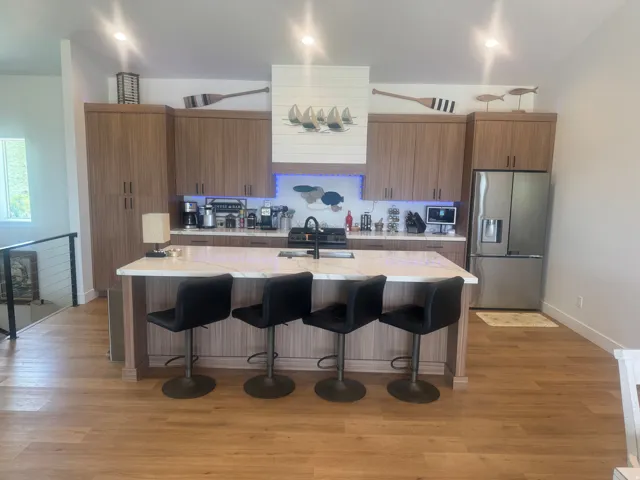 Contemporary kitchen featuring extensive wood-finish cabinetry, a large center island with a white stone countertop, and a stainless steel French door refrigerator