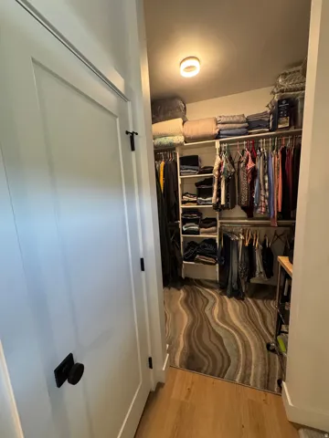 Walk-in closet featuring built-in shelving, multiple hanging rods, and a ceiling-mounted light fixture