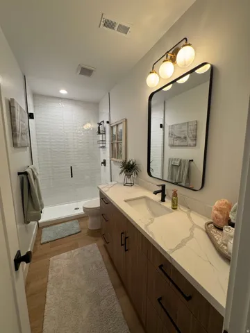 Contemporary bathroom featuring a wood-finish vanity with ample storage
