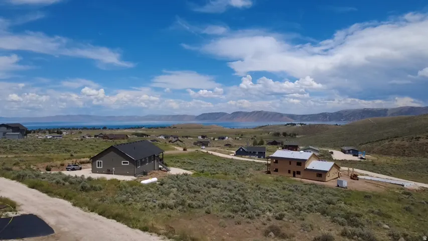 Property featuring a dark gray exterior, white window trim, and a covered porch, set on a natural landscape with a distant body of water and mountains