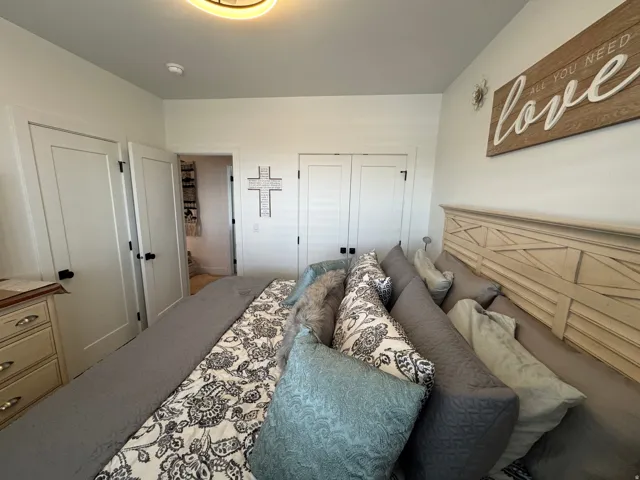 Bright bedroom featuring a decorative light fixture, white walls, and multiple doors with black hardware