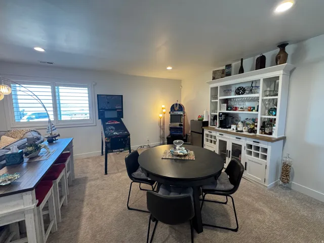 Spacious room featuring neutral carpeting, recessed lighting, white window shutters, and a prominent built-in hutch with open shelving and cabinet storage