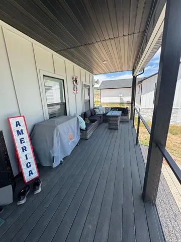 Expansive covered deck featuring composite decking, white vertical siding, and a dark soffit