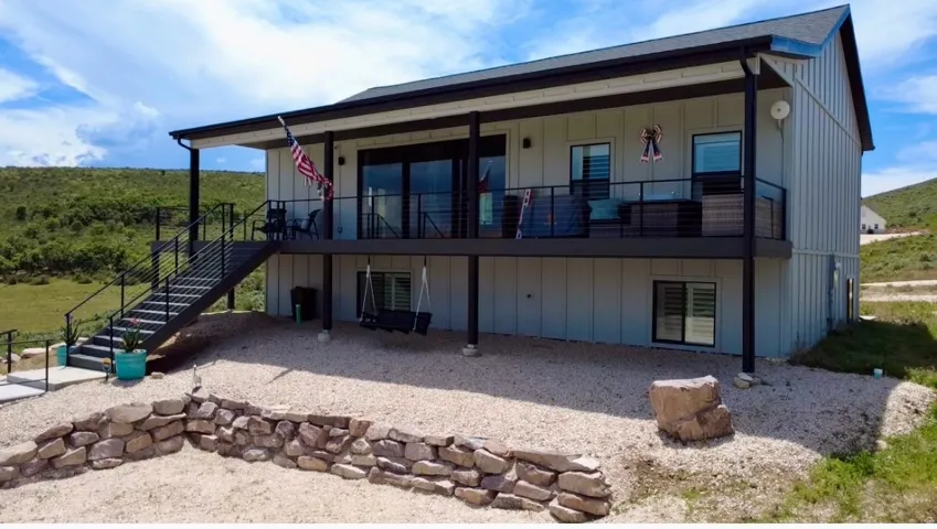 Contemporary two-story residence featuring a covered upper-level deck with black railing and exterior staircase