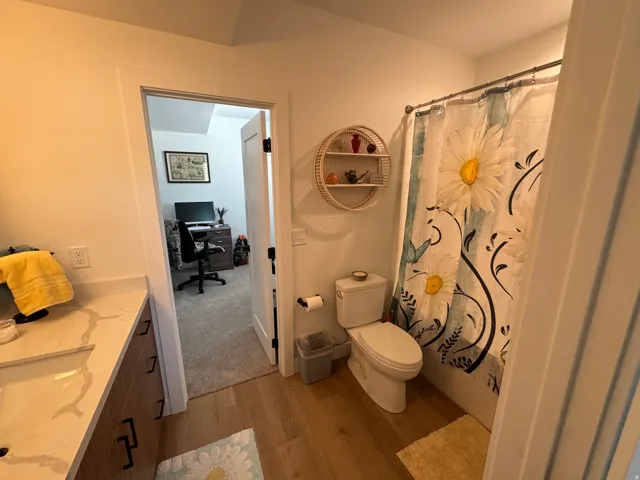 Bathroom featuring light wood-finish flooring, a white vanity with an integrated sink, dark cabinet hardware, and white walls