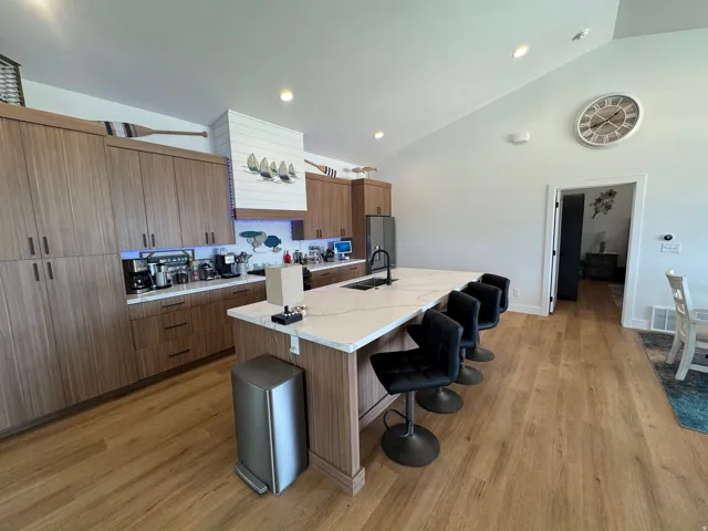 Spacious kitchen featuring a large island with seating, extensive wood-finish cabinetry, light countertops, and wood-finish flooring