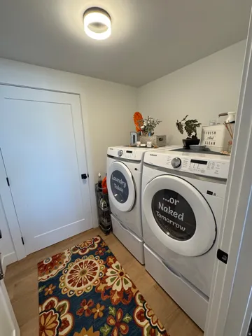 Dedicated laundry area featuring light-toned walls, wood-finish flooring, and a modern flush-mount ceiling light