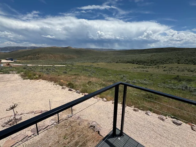 Expansive outdoor area featuring a cable railing system, gravel hardscaping, and natural rock accents
