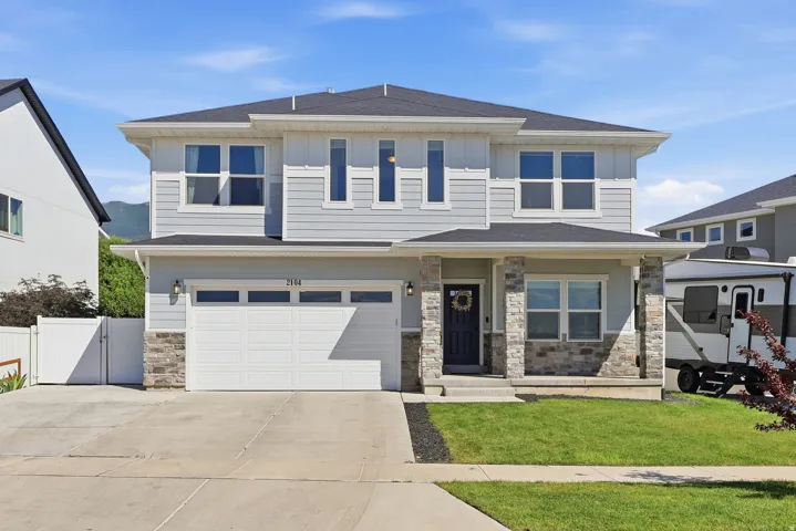 Two-story residence featuring light gray siding and stone veneer accents