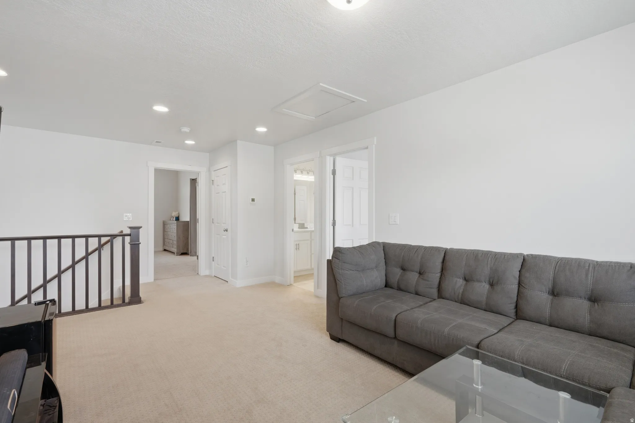 Carpeted bonus room with recessed lighting and a dark wood railing