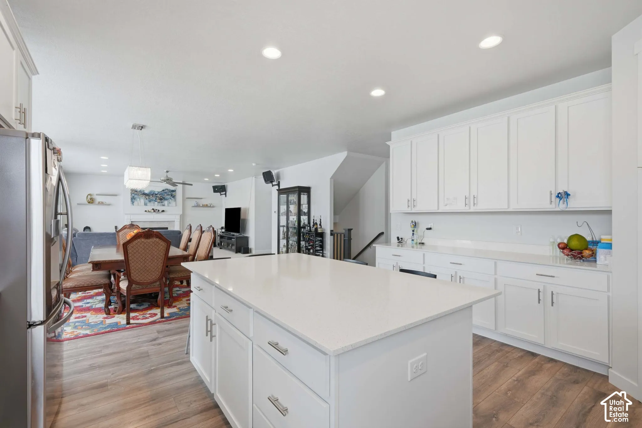 Expansive kitchen island with a light-colored countertop, white cabinetry, and wood-finish flooring