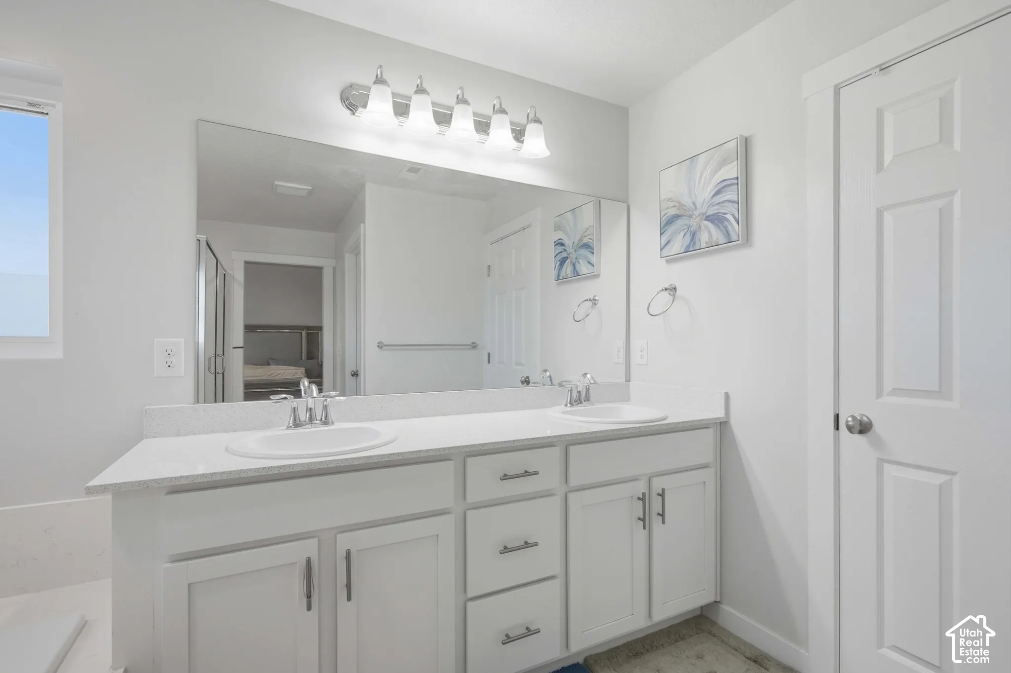 Double vanity with white cabinetry, integrated sinks, chrome faucets, and a large mirror
