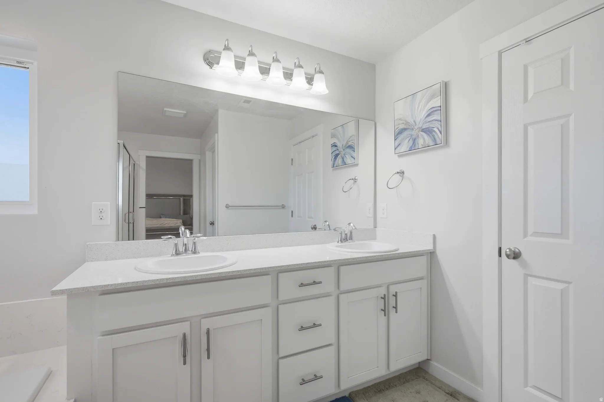 Double vanity with white cabinetry, integrated sinks, chrome faucets, and a large mirror