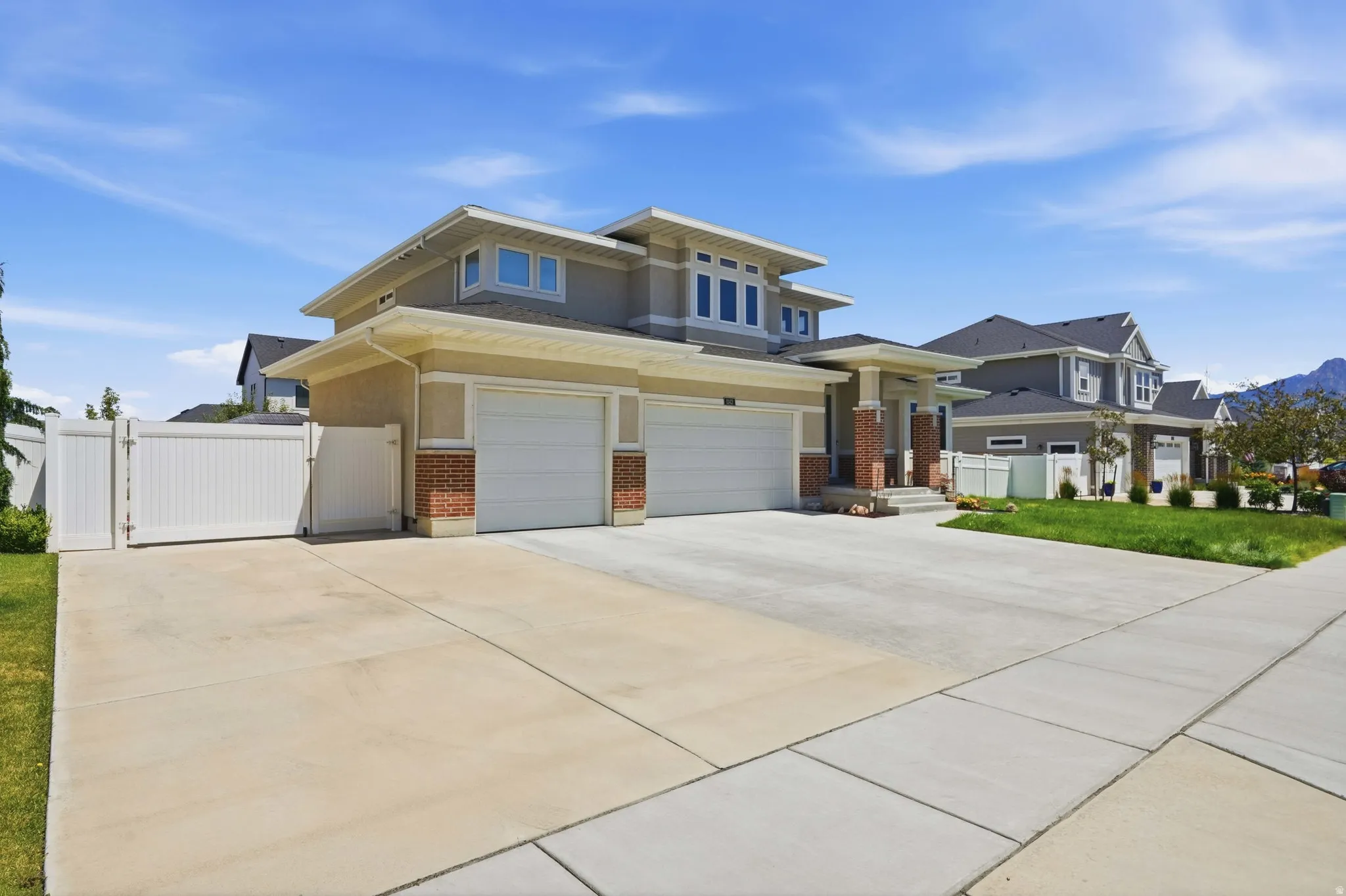 Contemporary residential exterior featuring a multi-level roofline, a two-car garage, and a brick facade accent