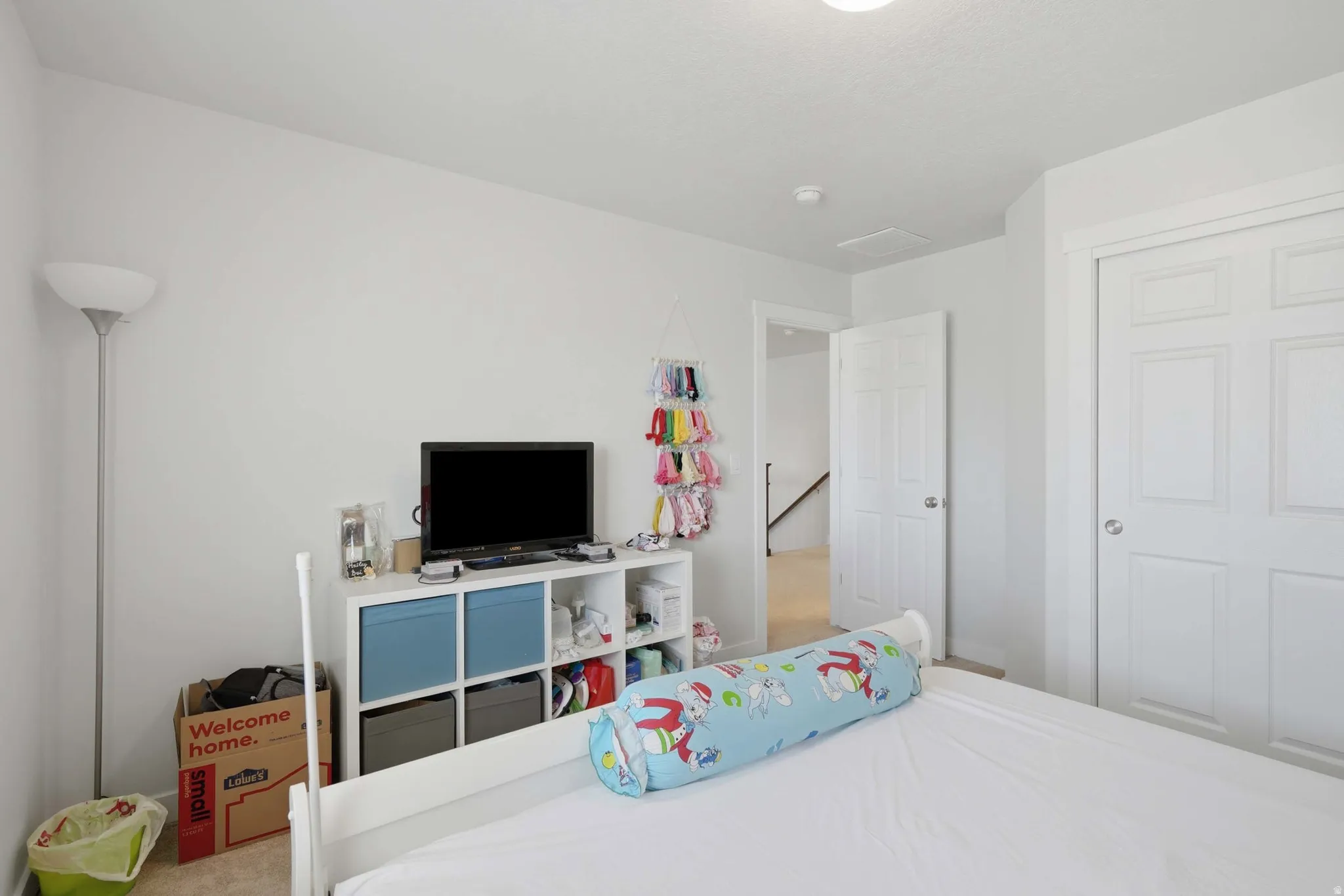 Bedroom featuring white walls, carpet flooring, a white six-panel door, and a white bi-fold closet door