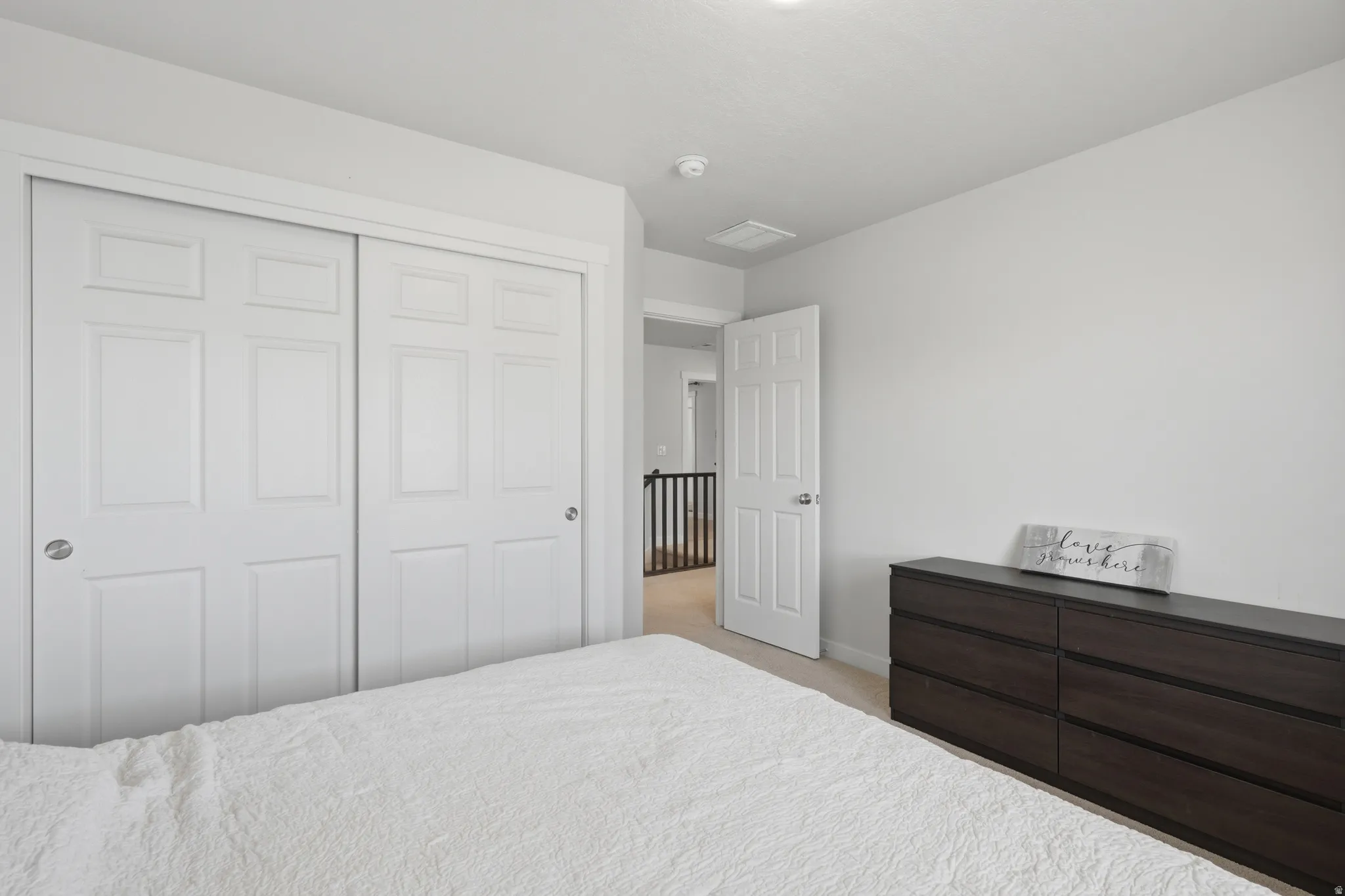 Spacious bedroom featuring dual sliding closet doors with six-panel styling, light neutral wall tones, and recessed ceiling lighting