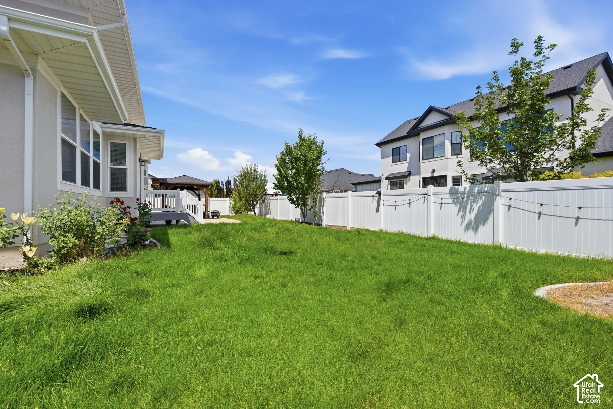 Expansive grassy yard with white vinyl fencing and string lighting