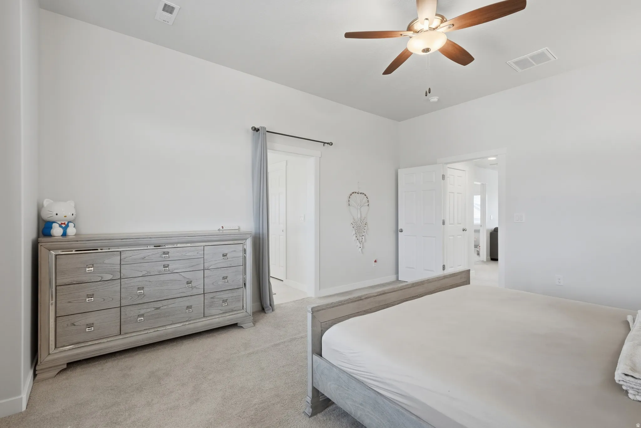 Carpeted room featuring a ceiling fan with integrated lighting, white walls, and a doorway with double bifold doors