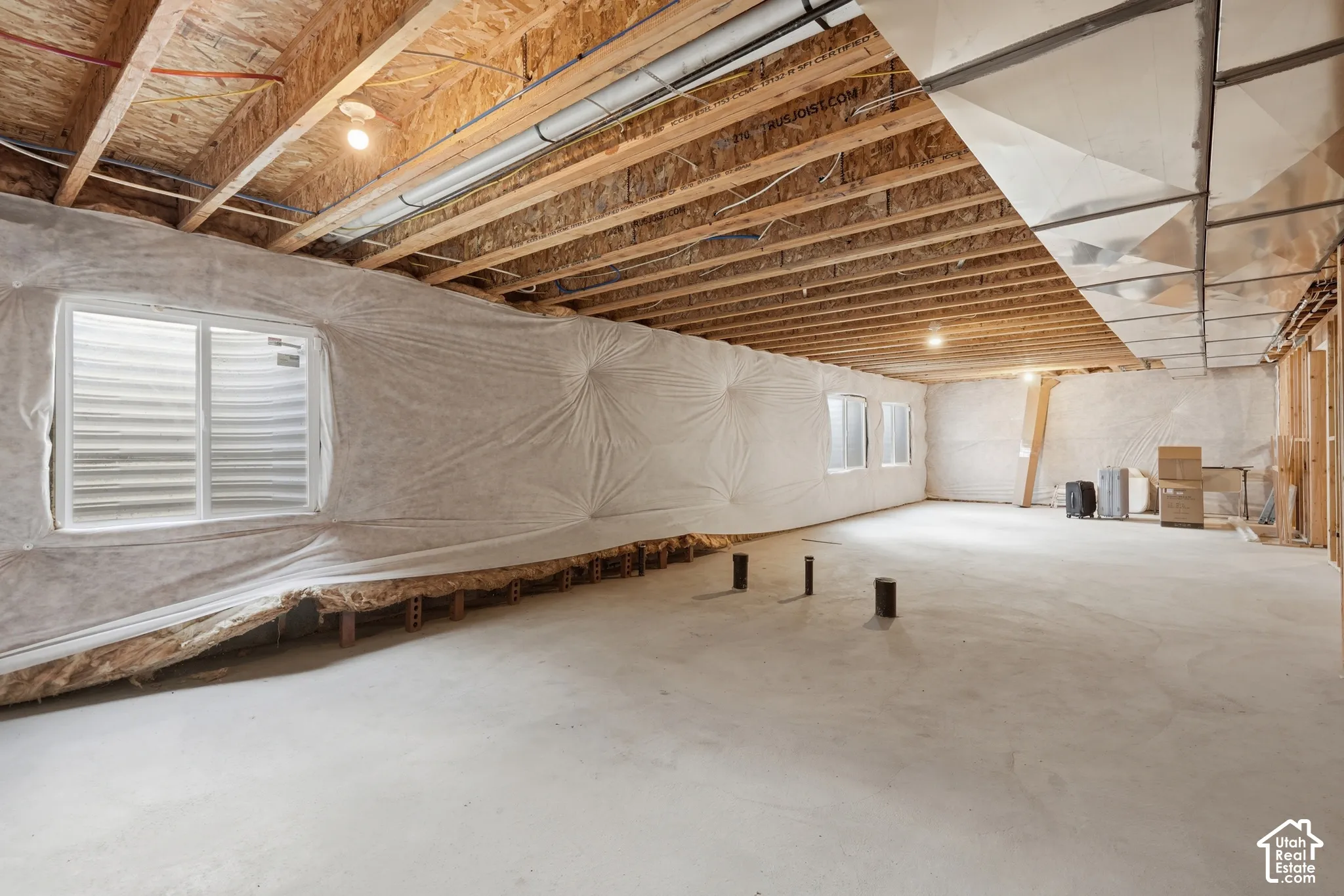 Unfinished basement featuring a concrete floor, exposed wood ceiling joists, and multiple egress windows