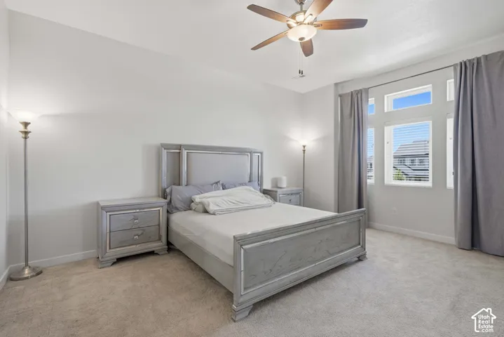 Spacious room featuring neutral carpeting, a ceiling fan with integrated lighting, and multiple windows with blinds and curtain rods