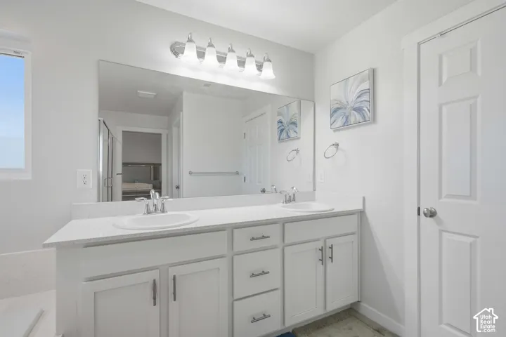 Double vanity with white cabinetry, integrated sinks, chrome faucets, and a large mirror