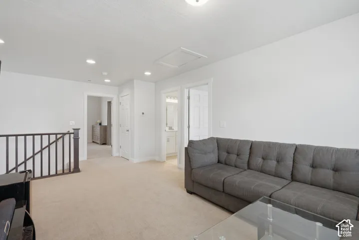 Carpeted bonus room with recessed lighting and a dark wood railing