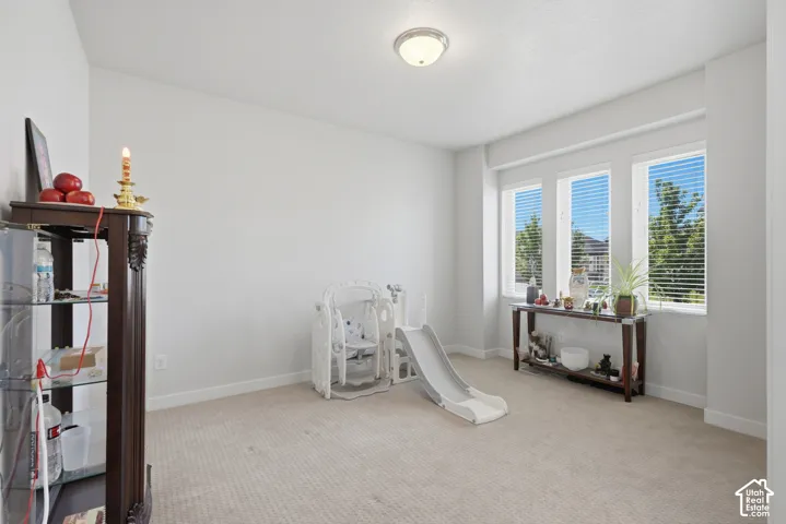 Bright room featuring three tall windows with horizontal blinds, neutral carpeting, and white walls