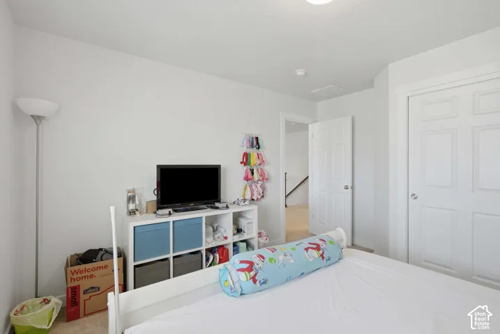 Bedroom featuring white walls, carpet flooring, a white six-panel door, and a white bi-fold closet door