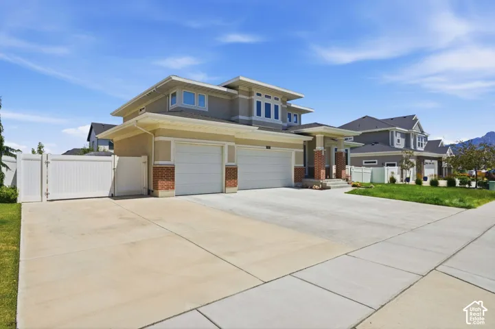 Contemporary residential exterior featuring a multi-level roofline, a two-car garage, and a brick facade accent