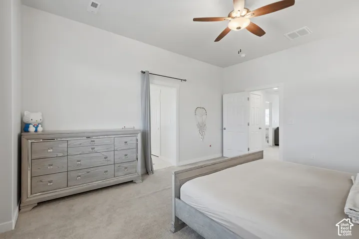 Carpeted room featuring a ceiling fan with integrated lighting, white walls, and a doorway with double bifold doors
