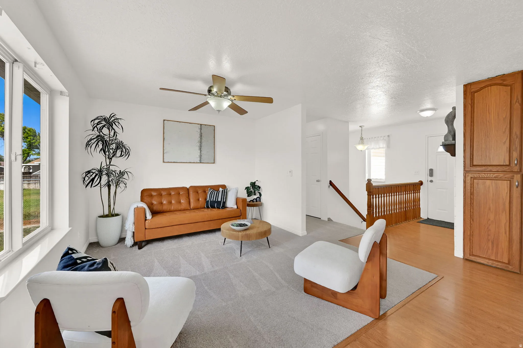 Living area with light gray carpeting and a ceiling fan