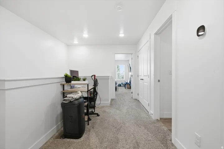 Carpeted hallway with white walls featuring chair rail molding
