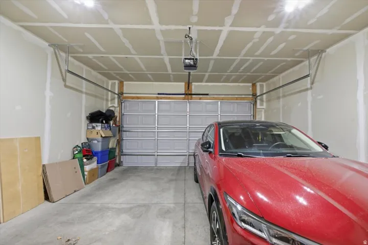 Interior garage featuring concrete flooring, a paneled garage door, and visible ceiling joists