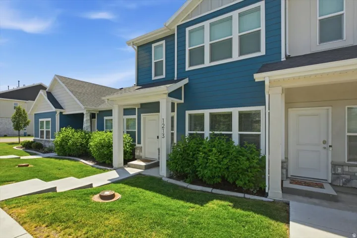 Modern townhome-style exterior featuring blue siding, white trim, and a covered entryway