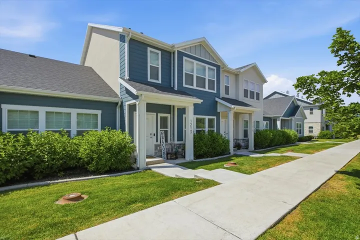 Modern townhome facade featuring blue siding, white trim, and a covered entryway