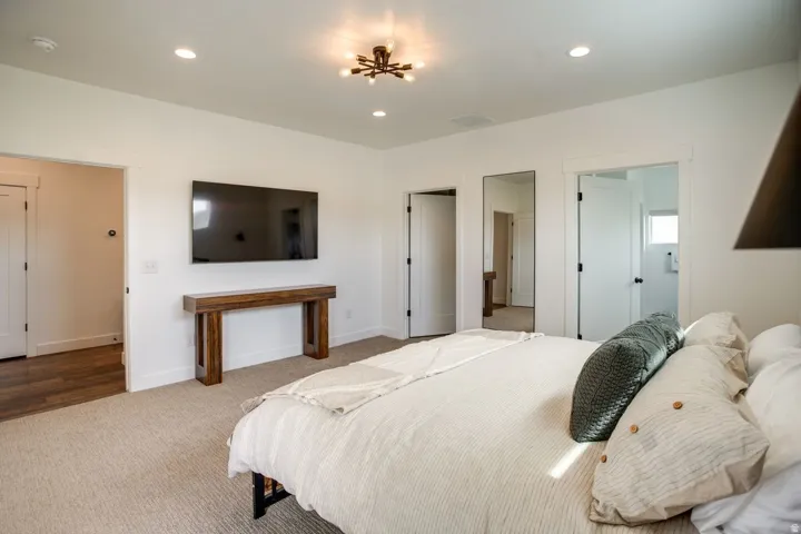 Spacious bedroom featuring light-colored carpeting, white walls, and a modern ceiling light fixture