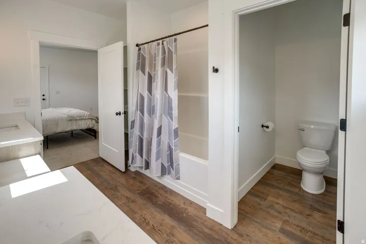Bathroom featuring wood-finish flooring, a white vanity with a light-colored countertop, and a shower-tub combination