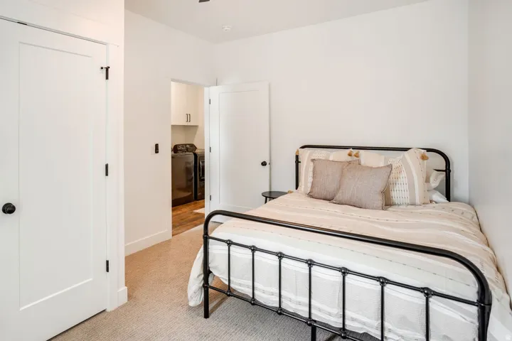 Bedroom featuring light-toned carpet flooring and a flat-panel interior door with matte black hardware