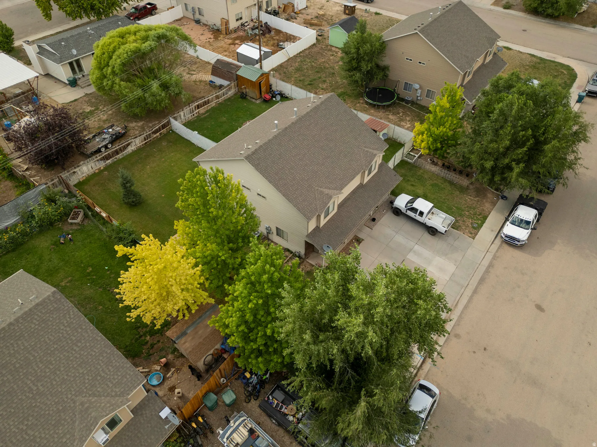 Two-story property featuring a tan exterior, dark shingle roof, and a concrete driveway
