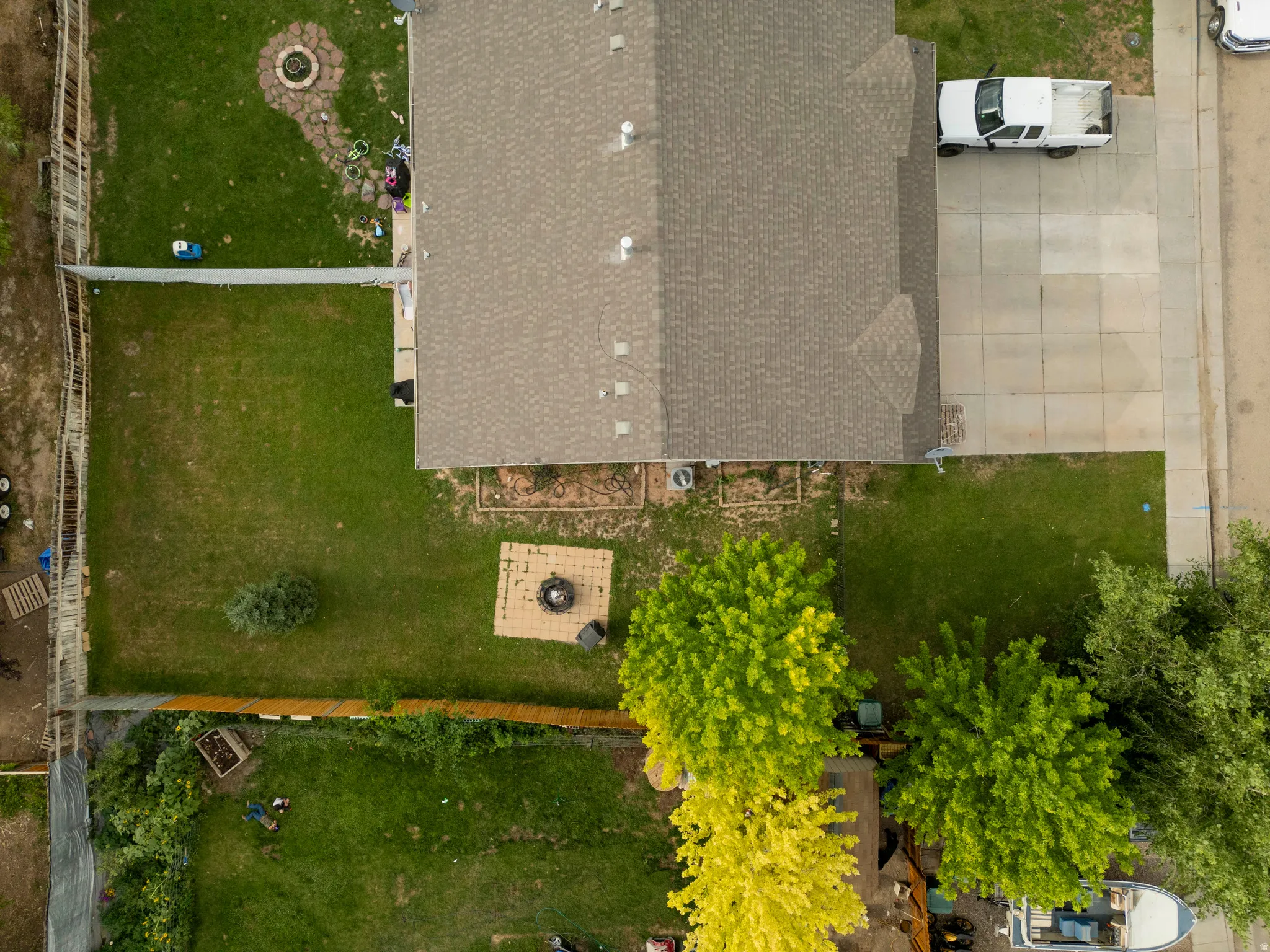 Expansive backyard featuring a manicured lawn, established trees, and a dedicated fire pit area