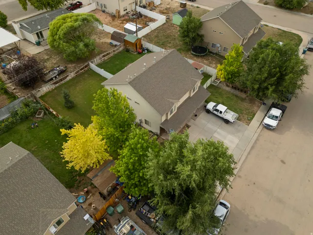Two-story property featuring a tan exterior, dark shingle roof, and a concrete driveway