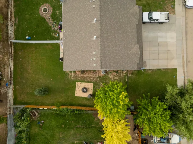 Expansive backyard featuring a manicured lawn, established trees, and a dedicated fire pit area