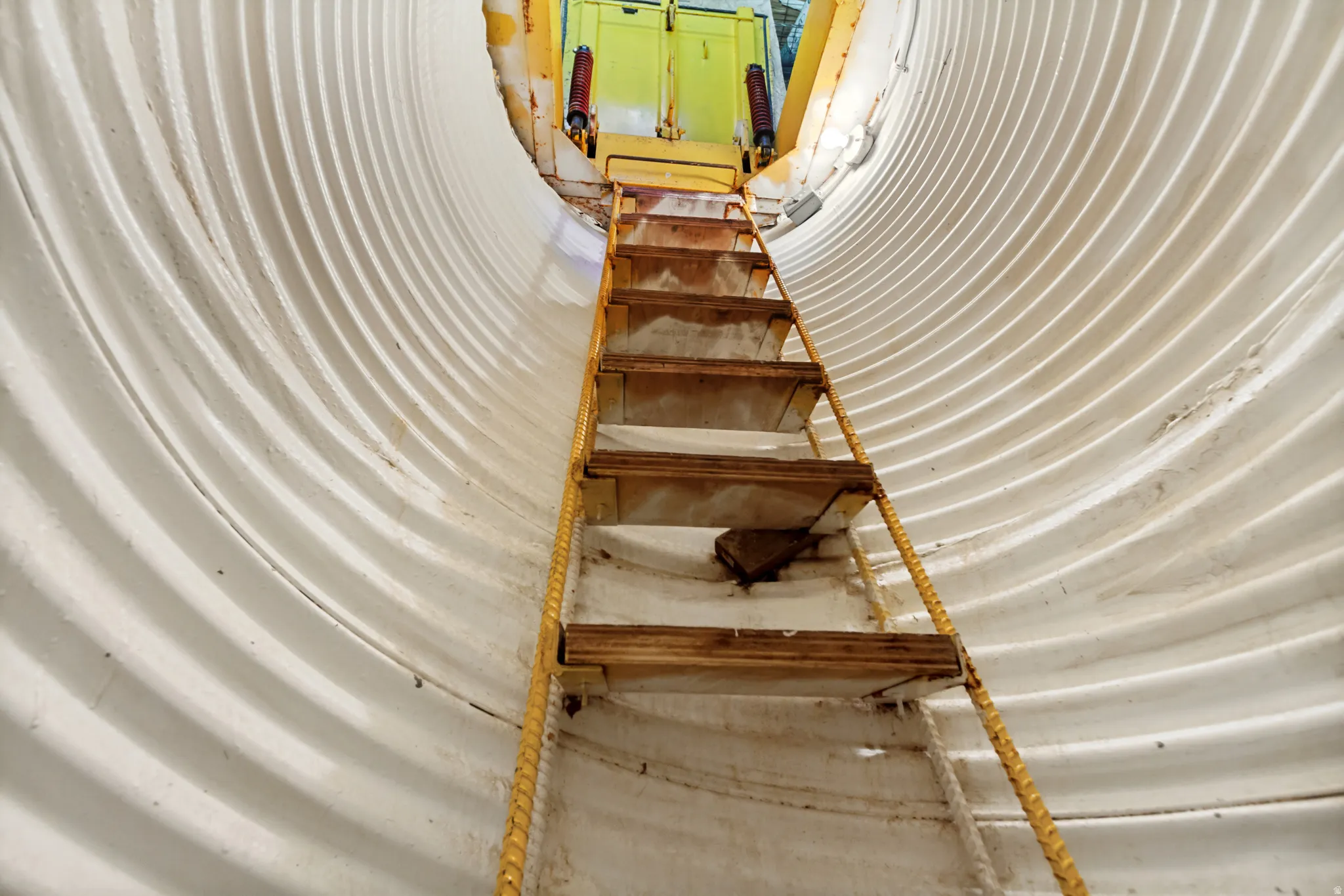 Corrugated metal interior with a wooden ladder leading to an upper platform
