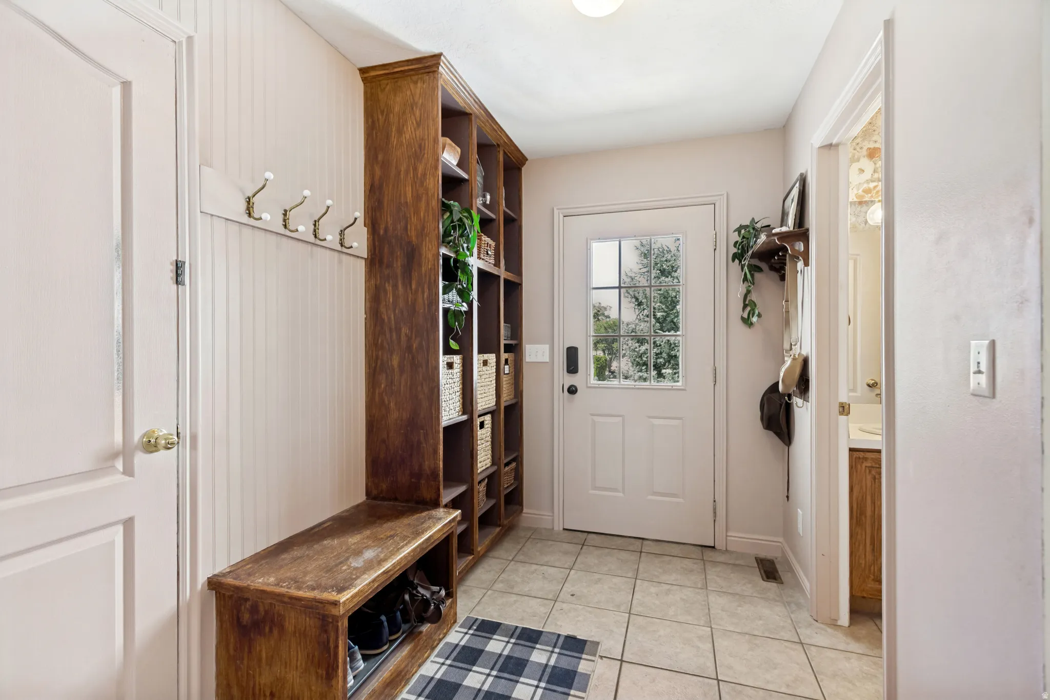 Built-in wood-finish shelving and bench with beadboard wainscoting